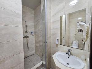 a bathroom with a sink and a shower with a mirror at GRAND Hotel in Zatoka