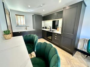 uma cozinha com armários pretos, cadeiras verdes e uma mesa em 4 The Nest Central Ripon em Ripon