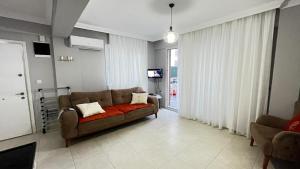 een woonkamer met een bank en een tv bij Elit Yaşam Site 1-Bedroom flat with pool in Fethiye