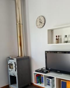 a living room with a television and a clock on the wall at Quinta do Paúl de Baixo in Guimarães