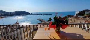 a table with two glasses and a vase of flowers on a balcony at LLOGUER30 Garbí Love, vistas espectaculares del mar in Sant Feliu de Guixols