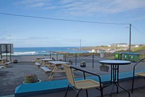 a patio with tables and chairs and a view of the ocean at Coast Lodge in Spanish Point