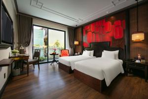 ホイアンにあるSilkian Hoian Boutique Hotel & Spaのベッドが2つあり、壁に絵が飾られたホテルの部屋