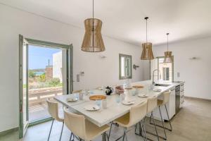 a dining room with a large white table and chairs at Villa Xifara - Seafront in Santa Maria