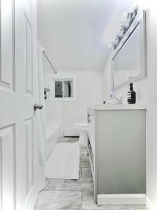 uma casa de banho branca com um lavatório e um espelho em Peaceful home equal to a sound sleep! em Mastic Beach