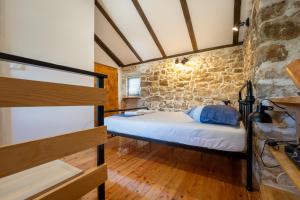 a bedroom with a bed and a stone wall at Kuća za odmor Nikola in Zadar