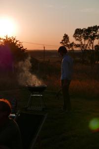 mężczyzna stojący przy grillu o zachodzie słońca w obiekcie Gorzelnia w Żarnowcu w mieście Żarnowiec
