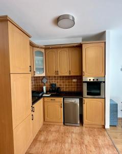 una cocina con armarios de madera y electrodomésticos de acero inoxidable en S3 Residences Ilka Studio Serviced Cozy Appartment, en Budapest