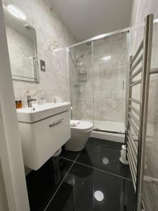 y baño con aseo, lavabo y ducha. en Acacia Hotel, en Londres