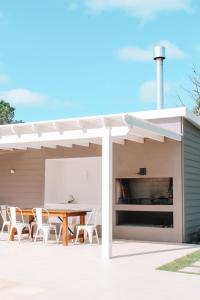 una zona de comedor al aire libre con mesa y sillas bajo una pérgola en Casa de mar - José Ignacio, en José Ignacio