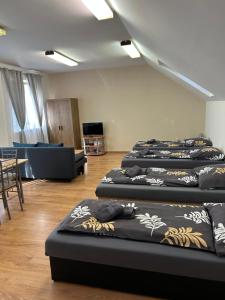 a room with four beds in it with a couch at Korzó Apartments in Dunajská Streda