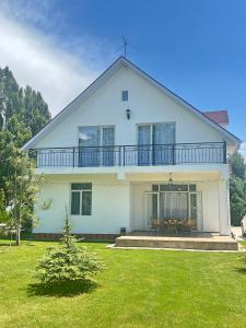 a large white house with a balcony and a yard at Двухэтажный коттедж с 2 апартаментами на озере in Dolinka