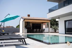 una piscina con sillas y una sombrilla junto a una casa en Villa Istra Relax Sapphire, en Rebići