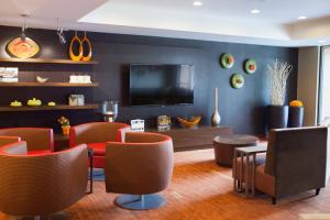 a living room with chairs and a flat screen tv at Courtyard Burlington Williston in Burlington
