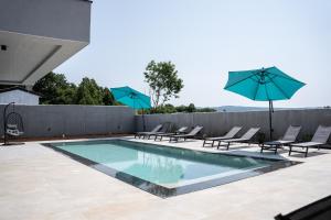 Una piscina con sillas y sombrillas en un patio. en Villa Istra Relax Sapphire, en Rebići
