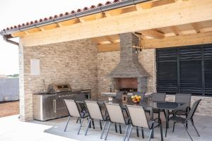 Un patio con mesa y sillas y una chimenea. en Villa Istra Relax Sapphire, en Rebići