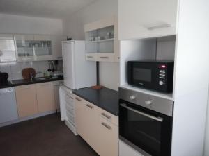 a kitchen with white cabinets and a black microwave at Ferienhaus Zum Heilbrunnen in Merzig