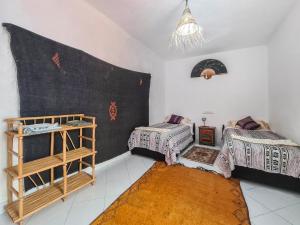 a room with two beds and a shelf in it at Riad MIYA in Essaouira