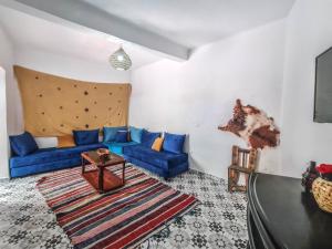 a living room with blue couches and a rug at Riad MIYA in Essaouira