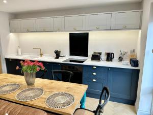 a kitchen with blue cabinets and a table with flowers at 6 The Feather in Ripon