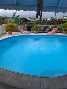 une grande piscine bleue avec des chaises sur un balcon dans l'établissement Lauraym 1, à Baie-Mahault