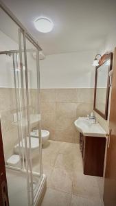 uma casa de banho com uma cabina de duche em vidro e um lavatório. em La Cattedrale Rooms em Assis