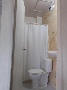 a white bathroom with a toilet and a shower at Hostel Santa Marta el Rodadero in Santa Marta