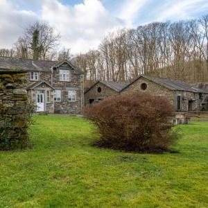 uma velha casa de pedra num campo de relva em Mill Cottage em Sawrey