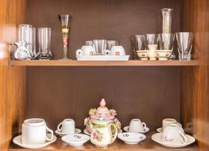 a shelf with a tea pot and cups and saucers at Accogliente Appartamento Centrale con Parcheggio in Foggia