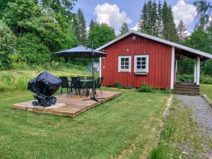 a picnic table with an umbrella in front of a red barn at Mieps Huset Dalarna Holiday in Kullen