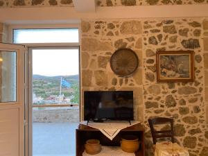 a living room with a television and a stone wall at Asterion Bella View in Zaros