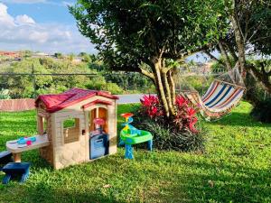 una casa de juguetes y una hamaca junto a un árbol en Casa Vacacional Nieves en PZ-Piscina Privada-WIFI, en San José
