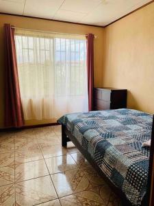 ein Schlafzimmer mit einem Bett und einem großen Fenster in der Unterkunft Casa Vacacional Nieves en PZ-Piscina Privada-WIFI in San José