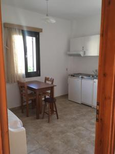 małą kuchnię ze stołem i krzesłami oraz oknem w obiekcie Iliachtida apartments w mieście Filótion