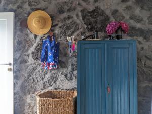 Casas do Horizonte في Ribeiras: خزانة زرقاء وقبعة من القش على الحائط