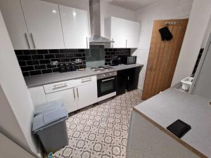 een kleine keuken met witte kasten en zwarte apparaten bij Cyfarthfa House in Cardiff