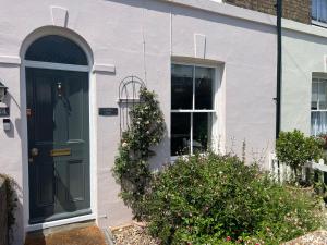 a white house with a green door and bushes at Cosy retreat, perfectly located just a min walk from Deal Beach and Castle in Deal