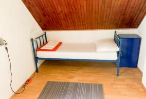 Cama pequeña en habitación con techo de madera en Plitvice RH Hostel Rooms, en Jezerce