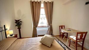 um quarto com uma cama, uma mesa e uma janela em La Cattedrale Rooms em Assis