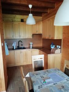 una cocina con armarios de madera, mesa y fregadero en Chata gościom rada, en Ustrzyki Dolne