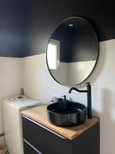 W łazience znajduje się czarna umywalka i lustro. w obiekcie Maison cosy avec jacuzzi w mieście Néant-sur-Yvel