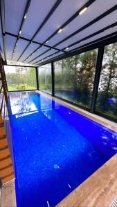 a large blue swimming pool in a building with windows at Emela Villa in Sapanca