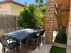 a table and chairs in a backyard with a brick wall at Beaux appartements climatisés - 3 pièces - espaces extérieurs - parking - proche plage in Hyères