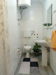 a white bathroom with a toilet and a sink at Apartments Doha in Ulcinj