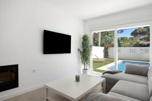 een woonkamer met een bank en een tv bij Villa Santa Clara 21c in Chiclana de la Frontera