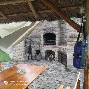 ein gemauerter Außenkamin mit einem davor stehenden Holztisch in der Unterkunft Mirella33 in Palić