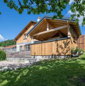 a house with a wooden facade with a green yard at La Chaume des Xettes / 10-14 pers SPA - Vue Lac in Gérardmer