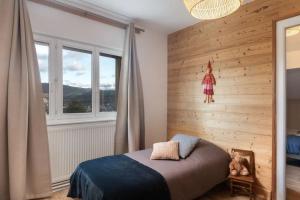 1 dormitorio con pared de madera, cama y ventanas en La Chaume des Xettes / 10-14 pers SPA - Vue Lac, en Gérardmer