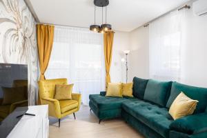 a living room with a green couch and yellow chairs at Penthouse Apartments East and West Star in Kaštela