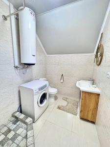 a bathroom with a washing machine and a sink at Двухэтажный коттедж с 2 апартаментами на озере in Dolinka